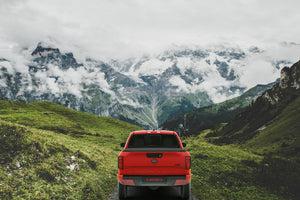 Red 2022 Nissan Frontier 6' Bed with an expanded Sawtooth Tonneau with a distant glacier covered mountain
