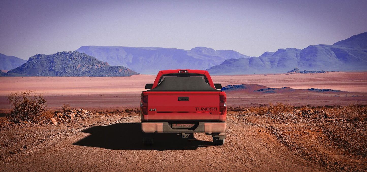 Red Toyota Tundra with an expanded Sawtooth Tonneau by a road with mountains in the background