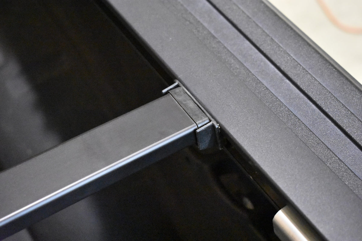 Close-up of a powder coated Sawtooth A.C.M.S. aluminum frame or bracket with a hinge-like joint and a small silver cylindrical component.