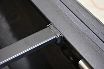 Close-up of a powder coated Sawtooth A.C.M.S. aluminum frame or bracket with a hinge-like joint and a small silver cylindrical component.