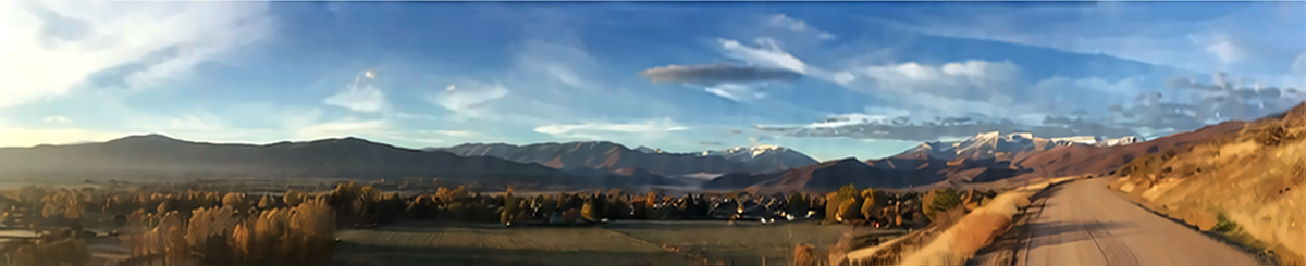 A scenic landscape photograph showing a winding dirt road leading through autumn fields toward distant mountains under a bright blue sky with wispy clouds.