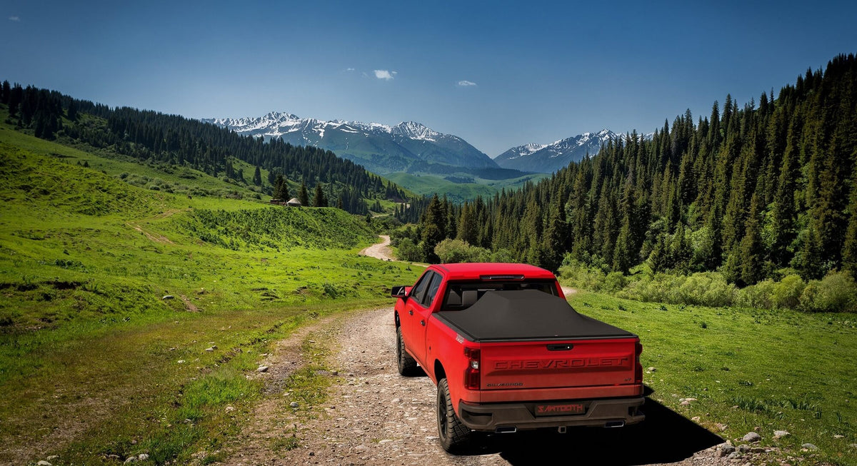 Red truck on a dirt road with mountains and trees in the background