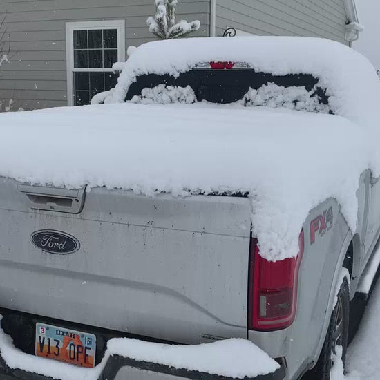 A sawtooth tonneau cover covered in snow with the tailgate opening.