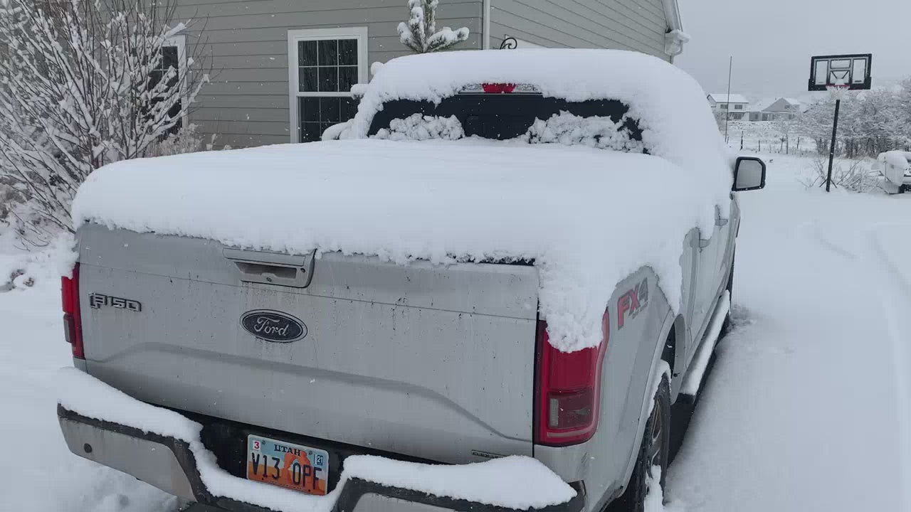 A sawtooth tonneau cover covered in snow with the tailgate opening.
