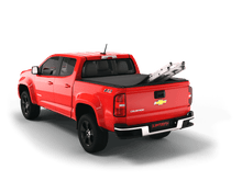 Load image into Gallery viewer, Red 2018 Chevrolet Colorado 5&#39; 2&quot; Bed / GMC Canyon 5&#39; 2&quot; Bed with ladder sticking out of Sawtooth Stretch expandable truck bed cover
