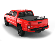 Load image into Gallery viewer, Red 2018 Toyota Tacoma 5&#39; Bed with ladder sticking out of Sawtooth Stretch expandable truck bed cover

