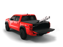 Load image into Gallery viewer, Red 2022 Nissan Frontier 5&#39; Bed with ladder sticking out of Sawtooth Stretch expandable truck bed cover with the tailgate open
