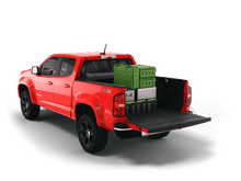 Load image into Gallery viewer, Red 2021 Chevrolet Colorado 5&#39; 2&quot; Bed / GMC Canyon 5&#39; 2&quot; Bed with gear in the truck bed and the Sawtooth Stretch tonneau cover rolled up at cab 
