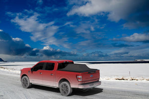 Red 2015 Ford F-150 5' 7" Bed with Sawtooth Stretch tonneau expanded over tall cargo load in the snow with blue skies