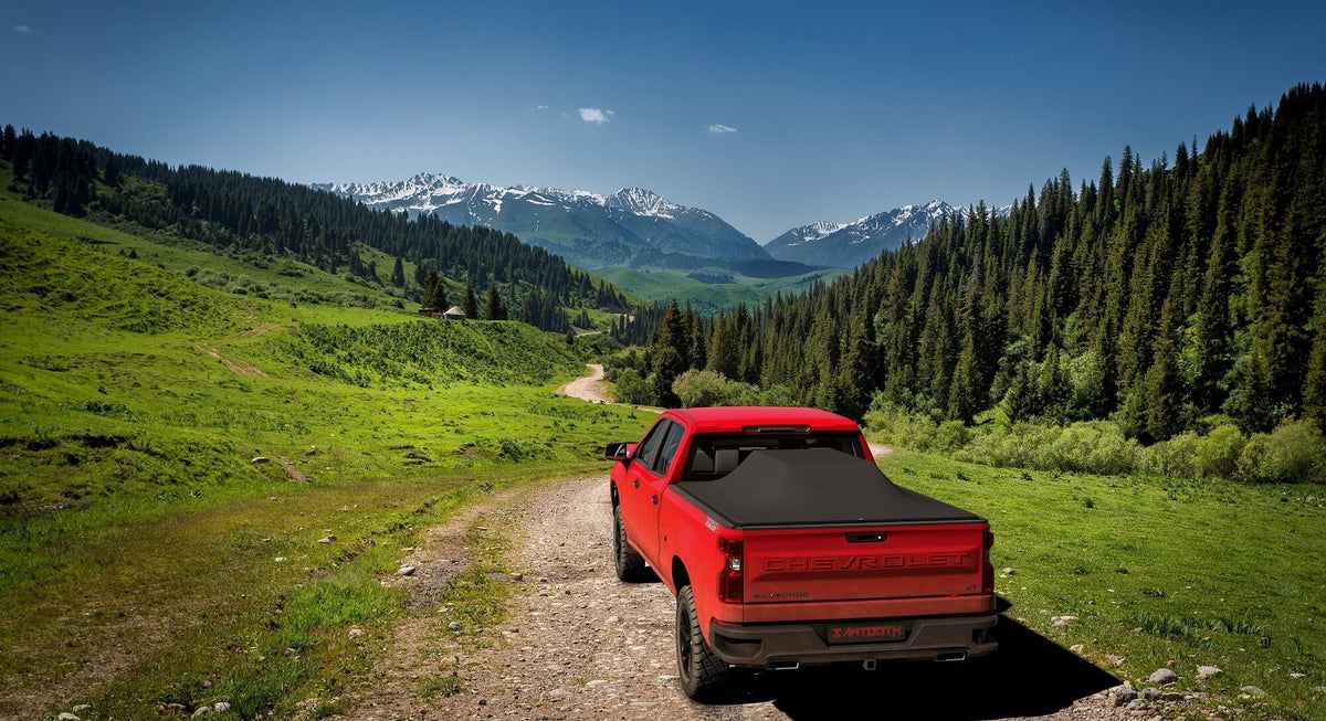 Red 2023 Chevrolet Silverado 2500 3500 6'-9" bed / GMC Sierra 2500 3500 6'-9" bed with large cargo under a Sawtooth Stretch expanded tonneau in the mountains