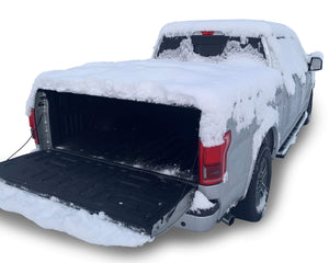 Silver Ford F-150 with Sawtooth Stretch truck bed cover lying flat covered in snow
