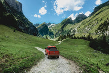 Load image into Gallery viewer, Red 2024 Ford Maverick with Sawtooth Stretch tonneau expanded over tall cargo load in narrow green mountain valley
